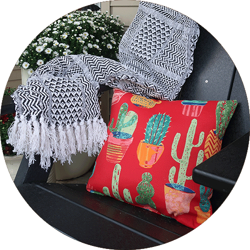 A red pillow with a cactus print next to a black and white blanket.